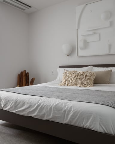Modern bedroom with dark wood bed, white bedding, cream textured pillow, and minimalist wall art above headboard